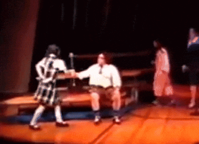 a blurry picture of a man sitting on a stage holding hands