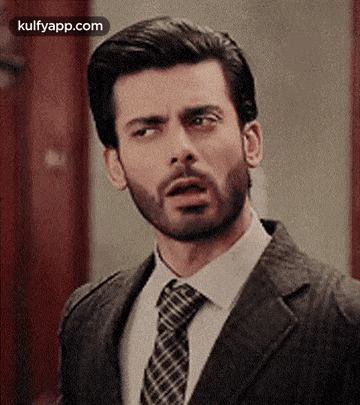 a man with a beard is wearing a suit and tie .