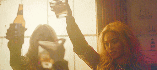 a woman holding a bottle of beer and a glass of water