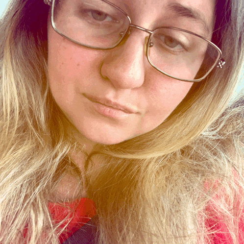 a woman wearing glasses and a red shirt is looking down