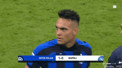 a man in a blue and black nike jersey stands next to another man on a field