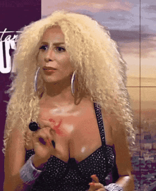 a woman with blonde curly hair is wearing a black and white dress