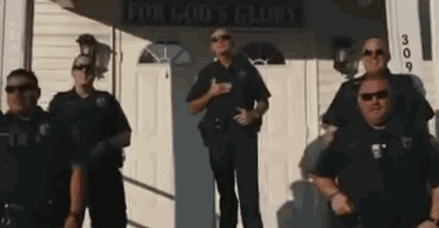 a group of police officers standing in front of a building that says for god 's glory