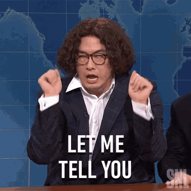 a man in a suit and glasses says " let me tell you "