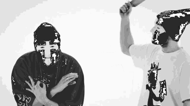 a man wearing a mask is holding a bat and another man wearing a shirt with the letter l on it is clapping