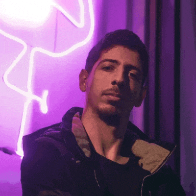 a man is standing in front of a purple neon sign