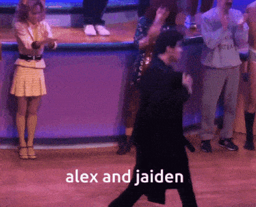 a man in a black coat is dancing on a stage with the words alex and jaiden above him