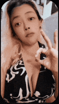 a woman in a black and white bikini top giving the peace sign