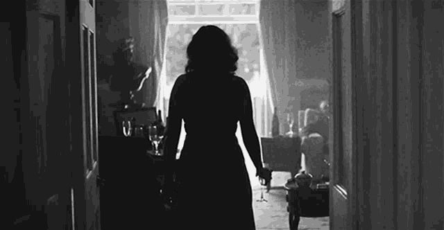 a woman in a dress is walking down a hallway .