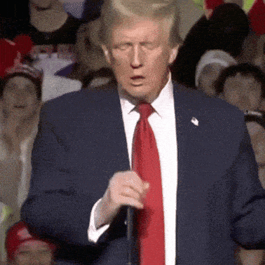 donald trump is wearing a blue suit and red tie while speaking into a microphone