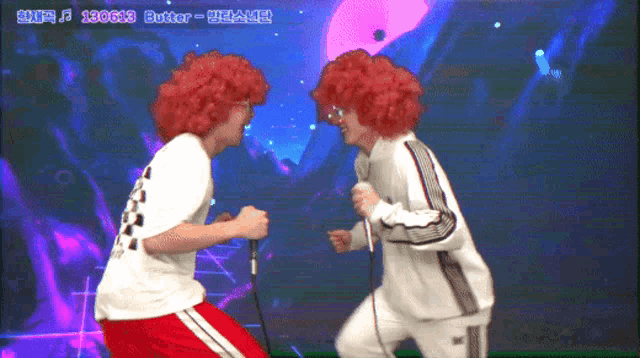 two men in red wigs are singing into microphones in front of a screen that says ' butter ' on it