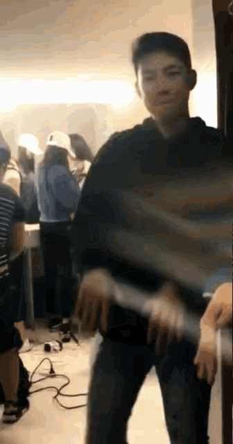 a man in a black hoodie is dancing in a crowded room .