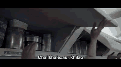 a person is reaching for a shelf in a kitchen with a caption that says `` chal khale aur khilao '' .