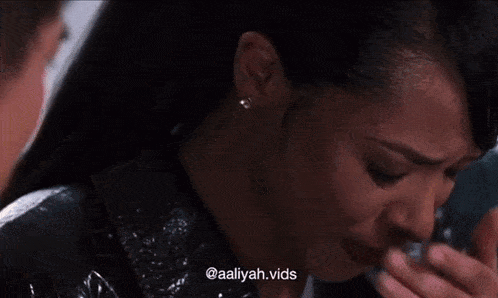 a woman with a ring on her finger is crying and covering her mouth with her hand .