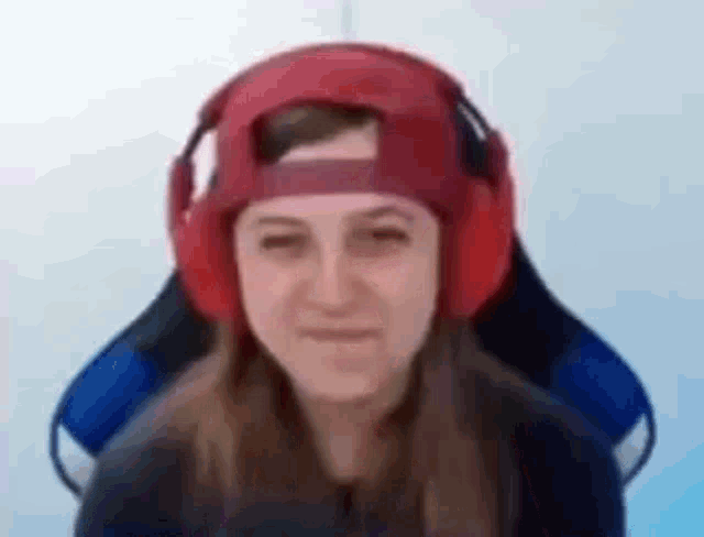 a woman wearing red headphones and a red hat is sitting in a chair .