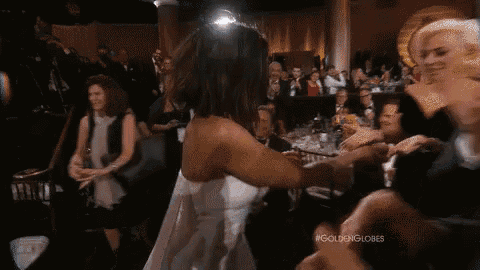 a woman in a white dress is dancing in front of a crowd at a gala .