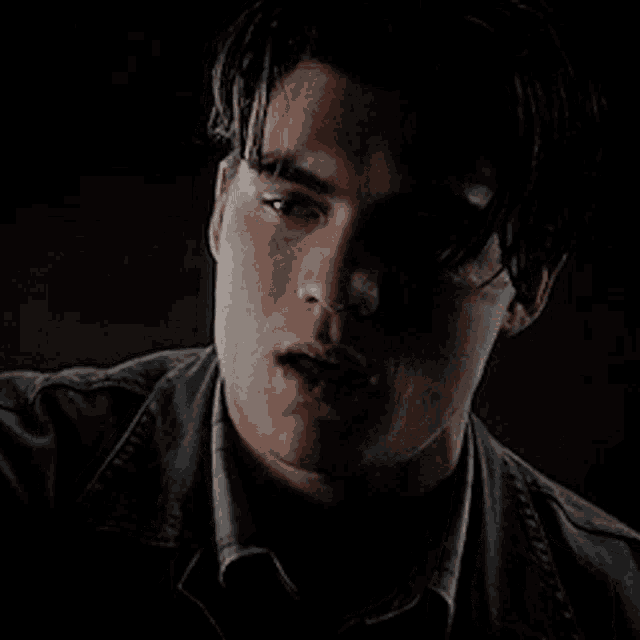 a close up of a man 's face in a dark room in a dark room .