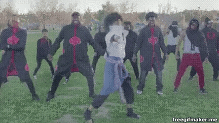 a group of people are dancing in a field in a park .