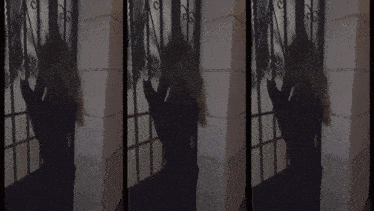 a woman in a black dress is standing in front of a white column
