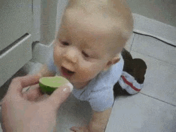 a baby is eating a slice of lime