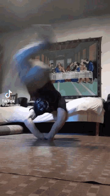 a tik tok video of a person doing a handstand in front of a painting