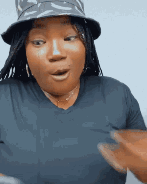 a woman wearing a bucket hat and a black shirt looks surprised