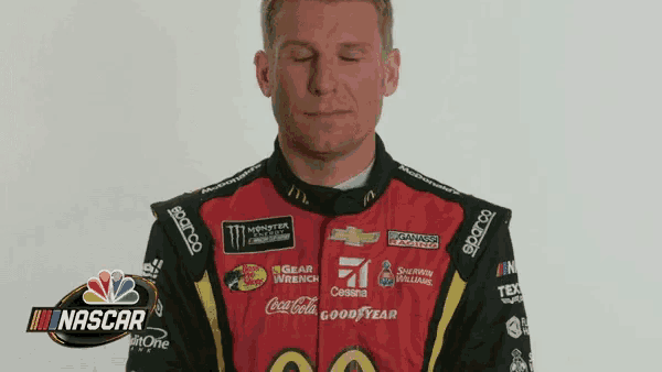 a man wearing a red and black racing suit with logos for coca cola and good year