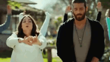 a man and a woman are dancing in a park while a group of people watch .