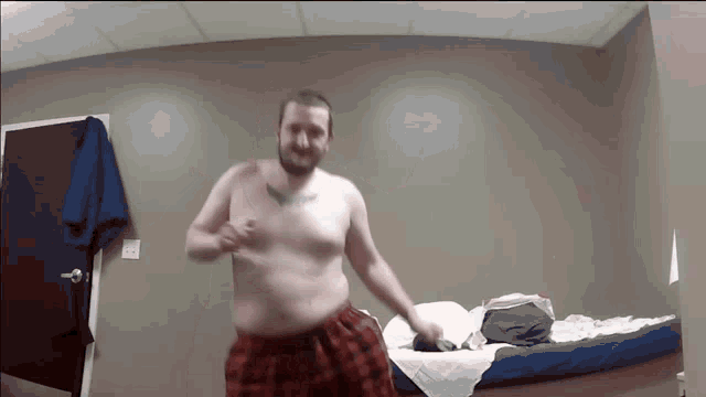 a shirtless man with a tattoo on his chest is dancing in front of a bed