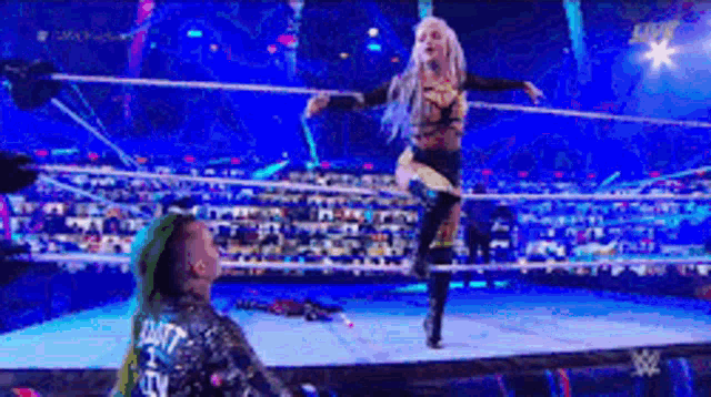 a woman with green hair is standing in a wrestling ring with a man .