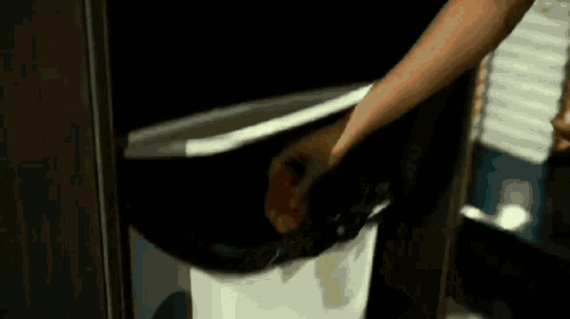 a person is throwing something in a trash can .