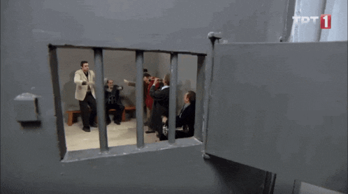 a group of men are behind bars in a prison cell with a sign that says tot 1 on it