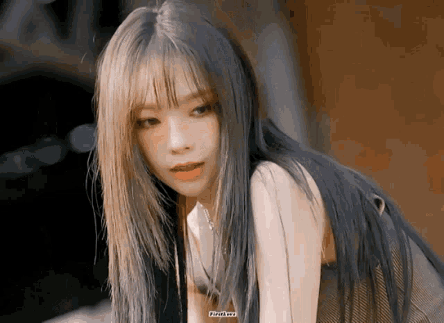 a woman with long hair and bangs is wearing a black top and a necklace .
