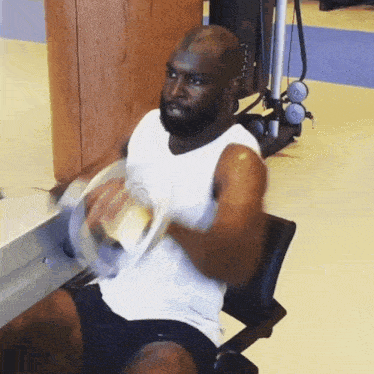 a man in a white tank top is doing exercises with a dumbbell