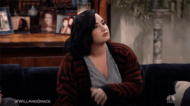 a woman sits on a couch with the hashtag #willandgrace on the bottom