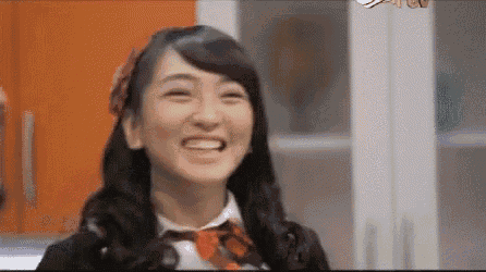 a woman in a school uniform is smiling in front of a cabinet .
