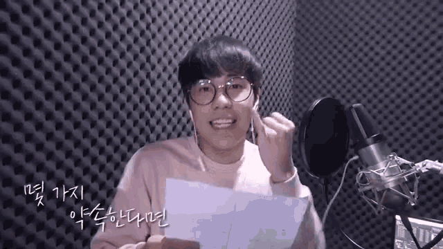 a young man wearing glasses is singing into a microphone .