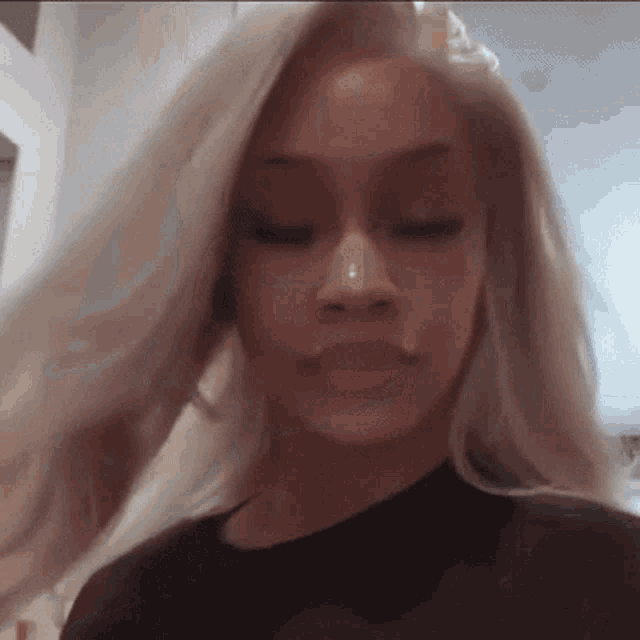 a woman with long blonde hair and a nose ring is looking at the camera .