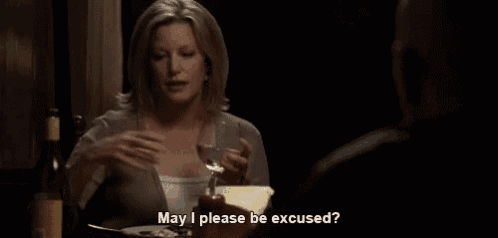 a woman is sitting at a table holding a glass of wine and saying " may i please be excused "