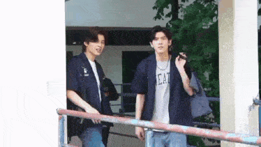 a couple of young men standing next to each other on a balcony .
