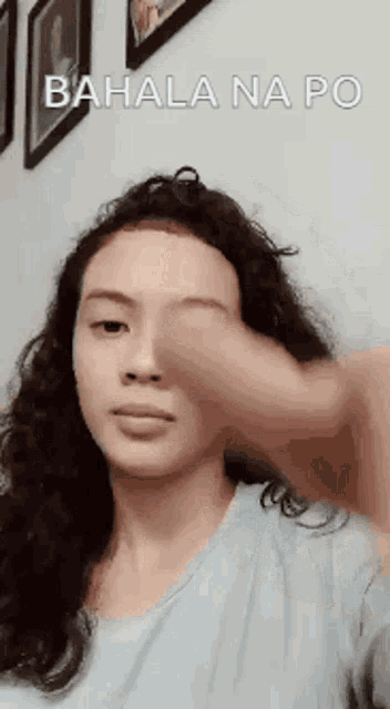 a woman is making a funny face while holding her hand to her forehead .