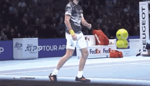 a tennis player is walking on a tennis court with a fedex sign in the background