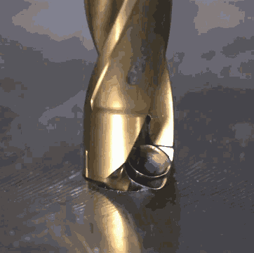 a close up of a gold drill bit with a reflection