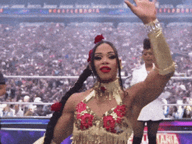 a woman in a gold and red outfit is waving her hand in front of a crowd