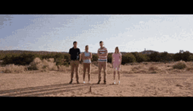 a group of people standing in a desert holding hands