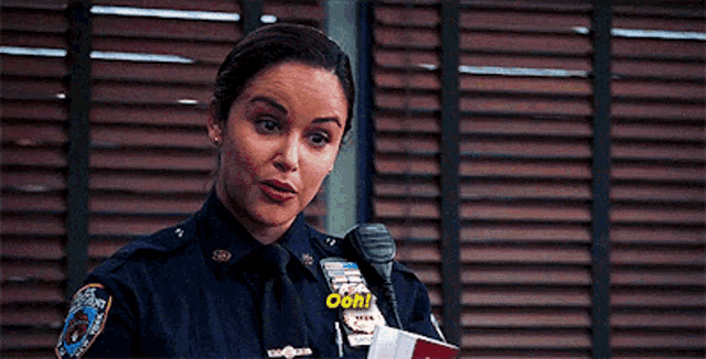 a woman in a police uniform is standing in front of a microphone and a book .