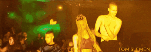 a man and a woman are dancing in a club with tom slemen written on the bottom right