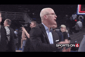 a man in a suit and glasses stands in front of a sports on 6 sign