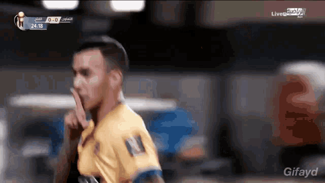 a soccer player holds his finger to his mouth while wearing a yellow jersey with the number 10 on it