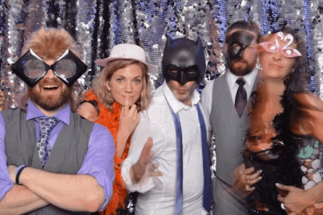 a group of people are posing for a picture with one wearing a batman mask